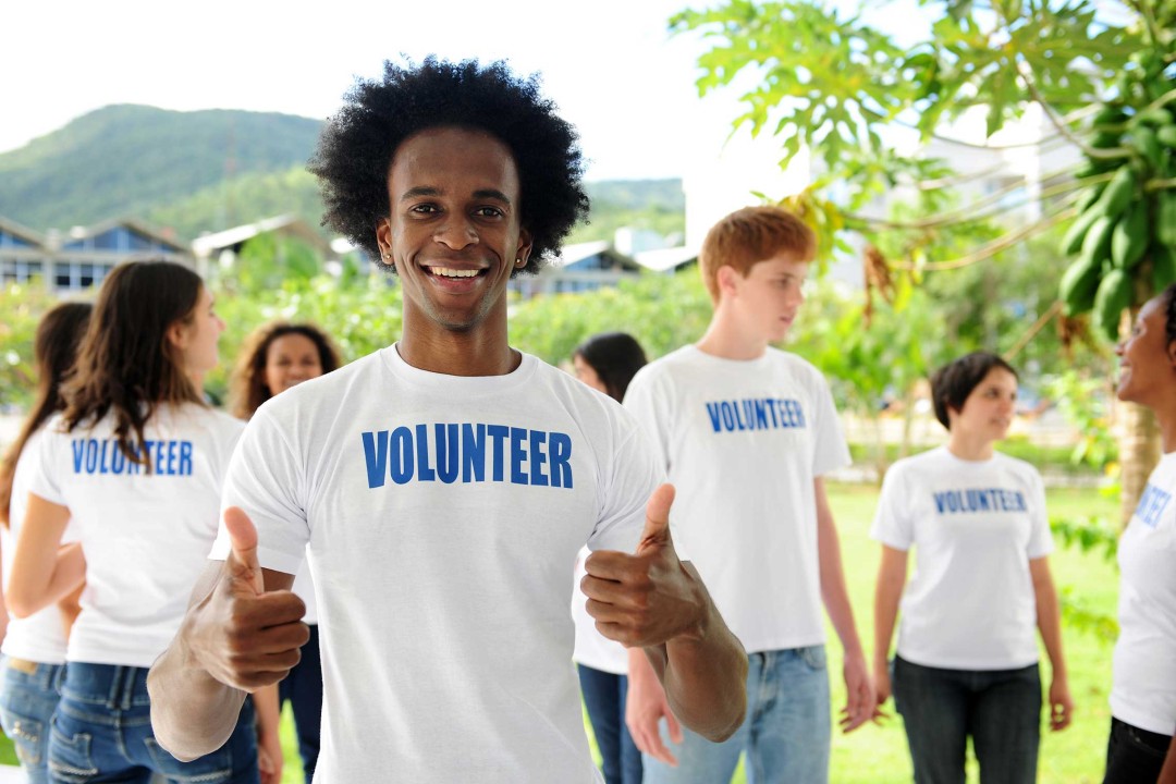 Image of several people wearing a volunteer shirt smiling at the camera